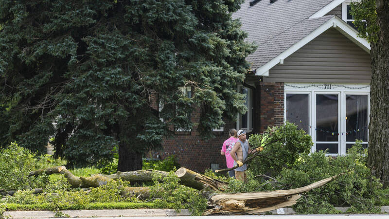 内布拉斯加州9日遭强风暴袭击。图为民众清理倒塌树木。（美联社）